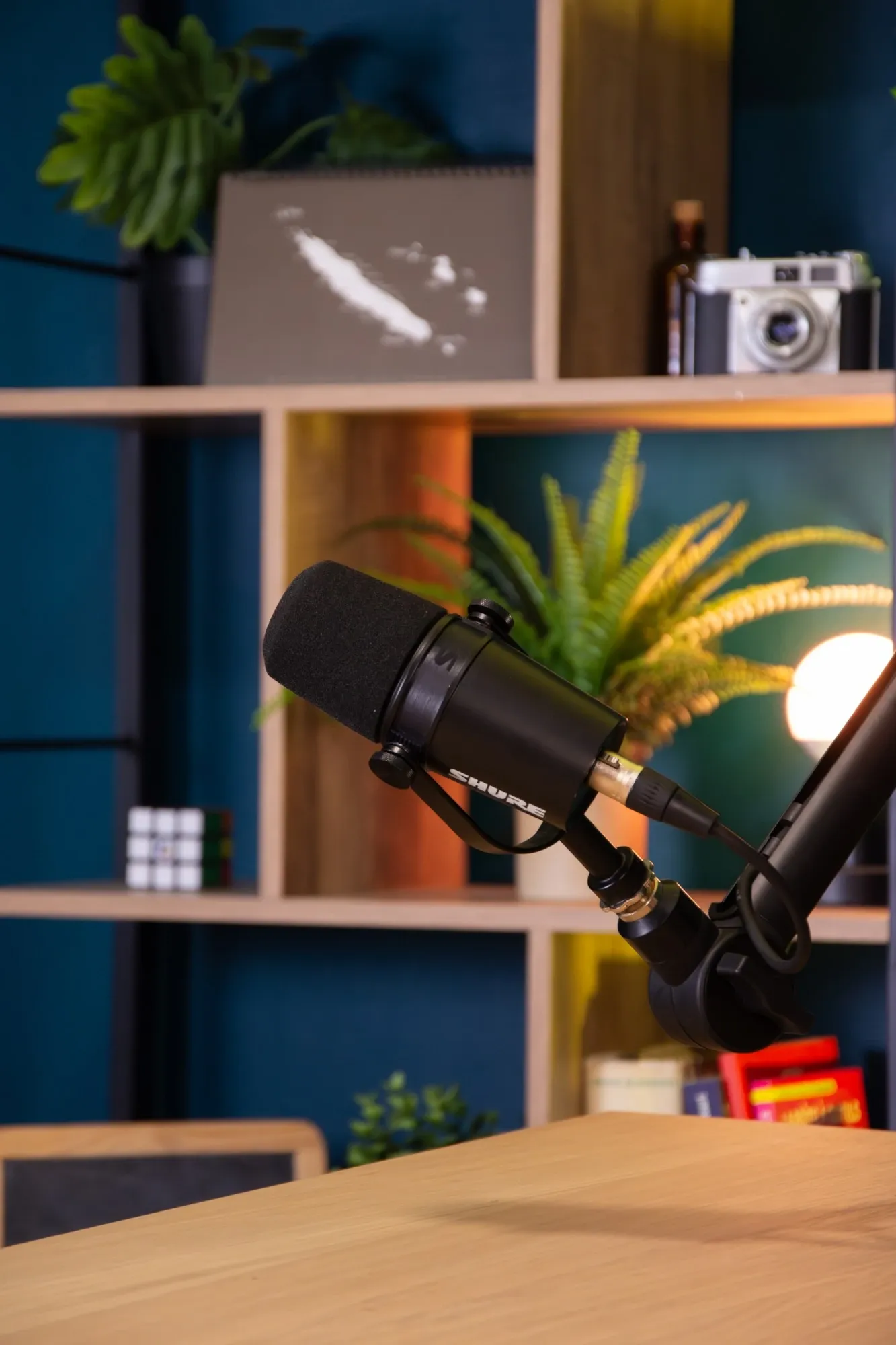 Un micro de podcast sur bras articulé, prêt devant l’étagère du studio.